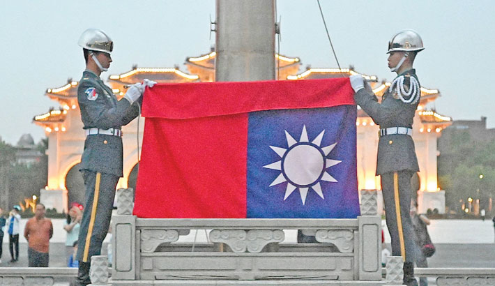 Honour guards fold a Taiwanese flag during a flag lowering ceremony at ...