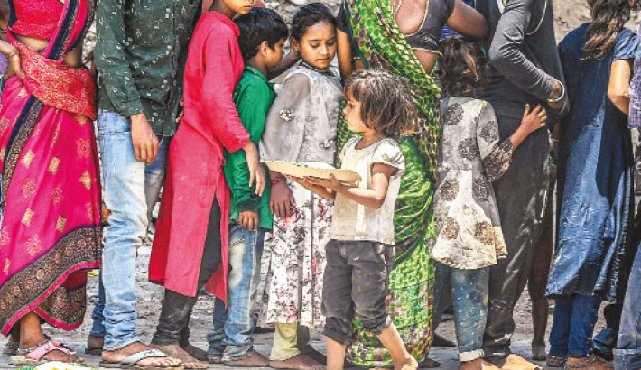 A child carries a plate after receiving free food being distributed as a charity by volunteers along a street in Hyderabad, Telangana, India on Thursday.-AFP PHOTO