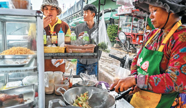 People buy street food from a roadside stall at Poipet town in Banteay Meanchey province in western Cambodia, on the border with Thailand, on 24 June 2025. Dozens of tourists and workers, some carrying children, were left stranded on 24 June at Thailand's main land crossing with Cambodia, after the army stopped almost all border traffic in an escalating territorial dispute. Photo: AFP