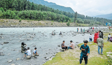 Tourists are pictured along a river in Pahalgam, about 112 km south of Srinagar on 26 June 2025. Photo: AFP