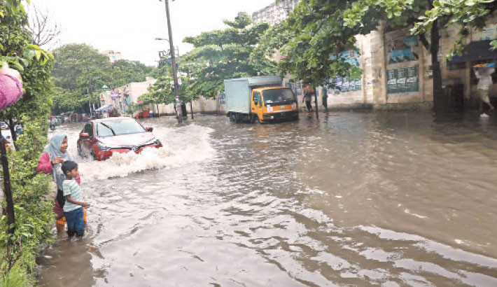 Vehicles struggle to navigate a waterlogged road in the capital’s New Market area, while a schoolchild and his mother wade through the flooded street. Heavy rainfall on Tuesday caused severe waterlogging in several parts of the capital, leading to significant disruption for commuters. -Reaz Ahmed Sumon