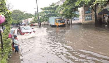 Vehicles struggle to navigate a waterlogged road in the capital’s New Market area, while a schoolchild and his mother wade through the flooded street. Heavy rainfall on Tuesday caused severe waterlogging in several parts of the capital, leading to significant disruption for commuters. -Reaz Ahmed Sumon
