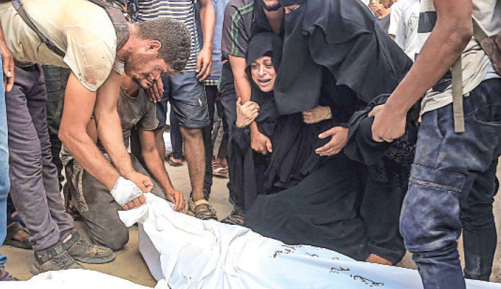 Palestinians grieve over the body of a man, killed at a food distribution point in Al-Tina area of Khan Yunis in the southern Gaza Strip, at the Nasser hospital on Saturday. AFP PHOTO
