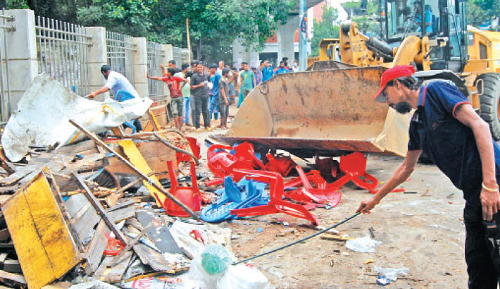A DSCC bulldozer demolishes illegal structures on footpaths and roads during a drive at TSC on the Dhaka University campus on Sunday. -Daily sun Photo