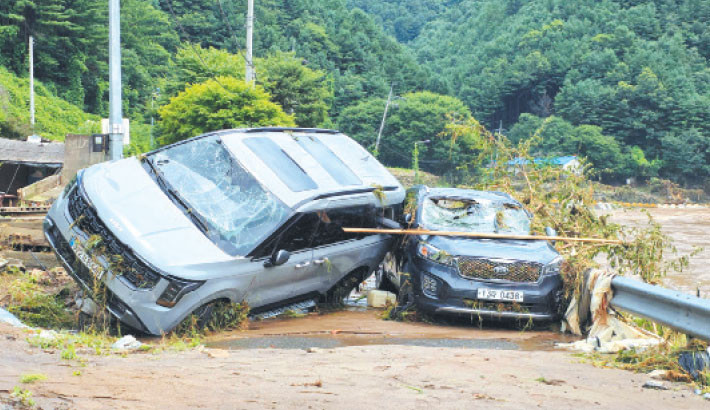 Cars damaged by floodwater are seen on a road along the river due to heavy rain in Gapyeong county, South Korea on Sunday. At least two people were killed during heavy downpours early on Sunday, the interior ministry said, bringing the death toll to 17 as South Korea has been hit by torrential rainfall this week.-AFP PHOTO