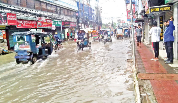 Vehicles crawl as pedestrians wade through ankle-deep water on a waterlogged road in Barishal Sadar on Friday, after days of continuous rainfall.  -  FOCUS BANGLA