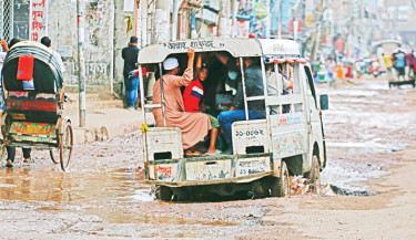 A tempo struggles to navigate a waterlogged, pothole-ridden road in the capital’s Jatrabari on Friday. The severely damaged road poses daily challenges for commuters and pedestrians alike, especially during the monsoon season. -Muktadir Mokto
