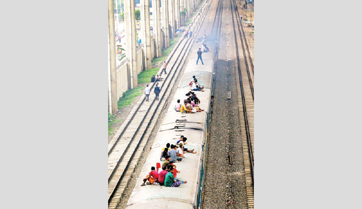 Passengers ride perilously on the roof of a train, putting their lives at risk. Such scenes are common in the country due to overcrowding and inadequate railway services. The photo was taken in the capital’s Mohakahali on Monday. Muktadir Mokto