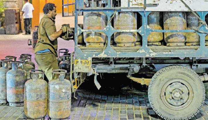 A worker unloads liquified petroleum gas (LPG) cylinders from a truck, parked outside a hotel at Church Street in Bengaluru, India, on Saturday. PHOTO: AFP