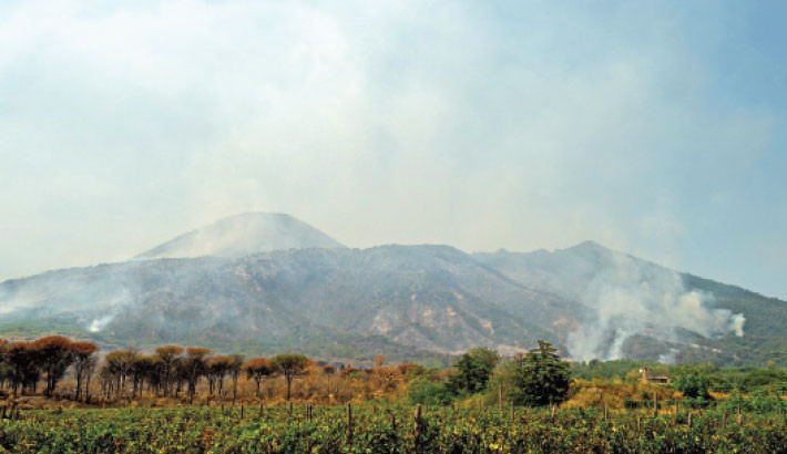 This photogoraph shows smoke rising from a wildfire at the Vesuvius National Park in Terzigno, near Naples on 10 August 2025. The national fire service said it had 12 teams on the ground and six Canadair planes fighting the blaze, which has torn through the national park in southern Italy since 8 August 2025. Photo: AFP