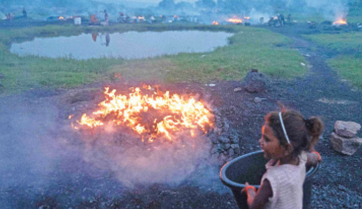 A young girl carries utensils past a heap of burning coal near an open-cast mine on the outskirts of Dhanbad, India, on Sunday. 

PHOTO: AFP