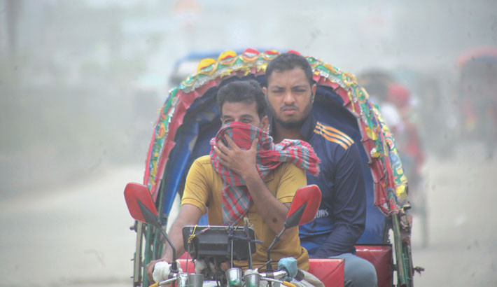 A battery-run rickshaw driver on the Mohammadpur-Gabtoli road in the capital’s Bosila area covers his face amid heavy dust engulfing the area on Saturday. - NAZMUL ISLAM