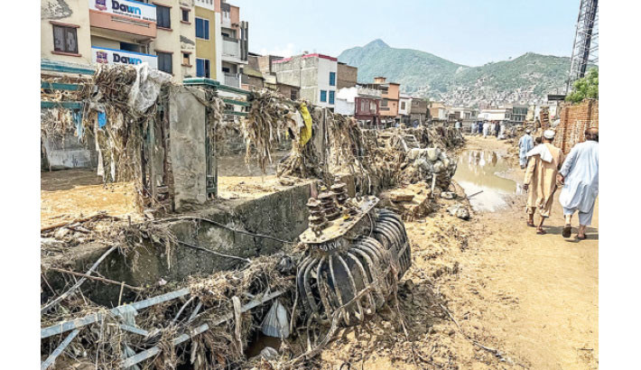People walk past scattered debris as floodwater flows near a damaged market following a flash flood in Mingora, the main city of Swat Valley, in monsoon-hit northern Pakistan's mountainous Khyber Pakhtunkhwa province on 16 August 2025. Photo: AFP