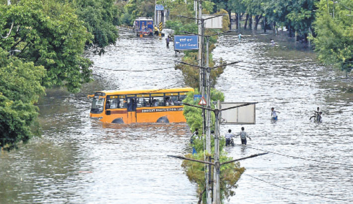 Commuters and school children wade through a flooded street after heavy rain showers in Jalandhar, Punjab, India on Wednesday.-AFP PHOTO