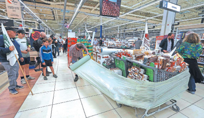 Members of the agricultural unions FDSEA 72 and Jeunes Agriculteurs (JA) farmer unions, wrap goods containing some acetamiprid, a neonicotinoid pesticide, during a protest operation at a supermarket in Mundolsheim, on Wednesday. Farmers in Burgundy and Alsace have recently denounced the ongoing sale to individuals of products containing the pesticide acetamiprid, despite the recent ban on its reintroduction in France for agricultural use. PHOTO: AFP