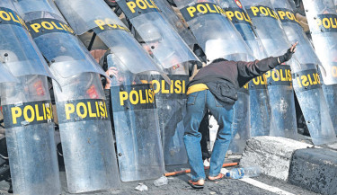 A protester charges against police as the latter hold positions behind their shields during a demonstration in front of the Bali police station in Denpasar, Indonesia Bali island, on Saturday. Indonesia was rocked by protests in major cities including the capital Jakarta on Friday after footage spread of a motorcycle taxi driver being run over by a police tactical vehicle in earlier rallies against low wages and financial perks for lawmakers. -AFP PHOTO