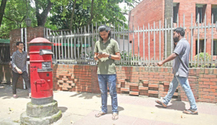 A post box at Dhaka University apparently stands only as a remnant of an almost bygone era of postal communication, while people roam around it – busy on their mobile phones – on Wednesday. - NAZMUL ISLAM