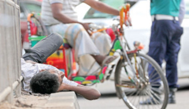 It is almost 10am, and the city roads are already crowded with vehicles ferry-ing people to their workplaces. Traffic police are busy directing the unruly traffic. A young man sleeps soundly on the island of a Metro Rail pillar at Dainik Bangla intersection in Dhaka on Wednesday. A single misstep could result in a tragic accident, highlighting the vulnerability of homeless people.   -  KAMRUL ISLAM RATAN