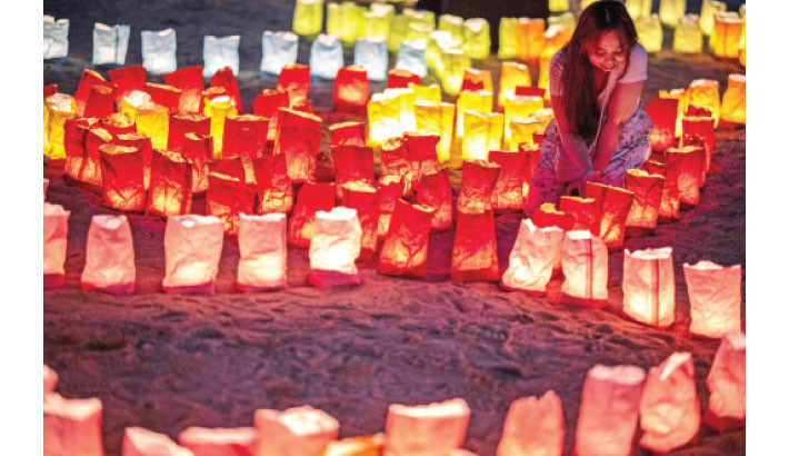 A visitor poses on the beach during the Odaiba Lantern Festival at Odaiba Marine Park in Tokyo on Sunday. –AFP Photo