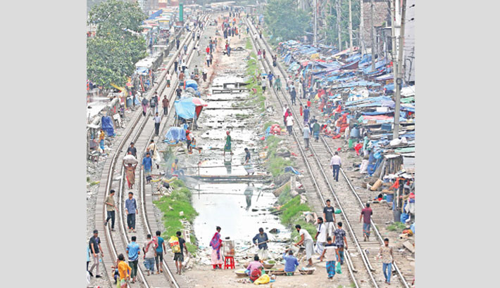 People walk along the rail tracks near Malibagh rail gate as the pavements remain occupied by makeshift shops, forcing pedestrians onto the risky path. The photo was taken on Monday. Kamrul Islam Ratan