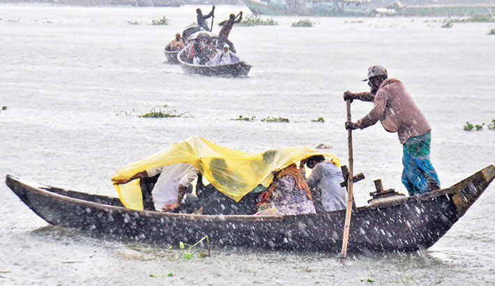 People cross the River Buriganga on boats near Sadarghat in Dhaka amid rain on Monday noon. Focus bangla