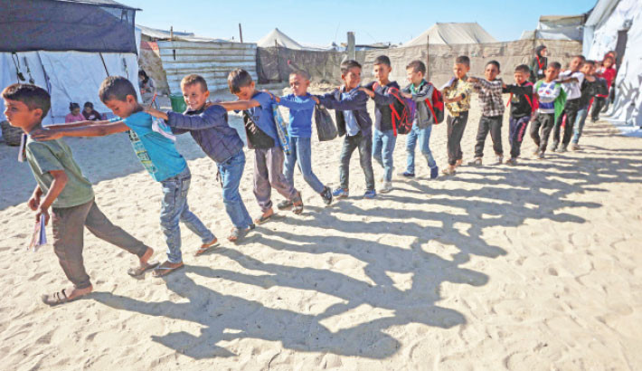 Palestinian pupils walk in a queue out of a tent used as a classroom at a school set up by the Mayasem Association for Culture with UNICEF support, at a displacement camp in the al-Qarara area of Khan Yunis in the southern Gaza Strip on Tuesday. The school dispenses classes to 1500 pupils on basic academic subjects in addition to arts such as drawing, music, and the traditional Tatreez embroidery as part of preserving Palestinian heritage.-AFP PHOTO