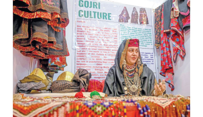 A woman dressed in traditional tribal attire sits at a stall during an exhibition and sale of rural arts and crafts organised by the Jammu and Kashmir Rural Livelihood Mission (JKRLM), in Srinagar on 8 October 2025. Photo: AFP