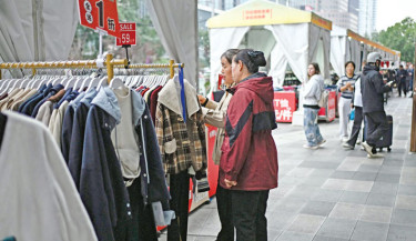 Two women select clothes at a open market in Beijing on 16 October 2025. 	PHOTO:  AFP