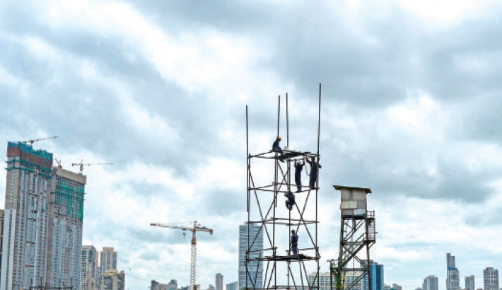 Workers are seen on a scaffolding tower during a cloudy afternoon in Mumbai, India, on Sunday. PHOTO: AFP