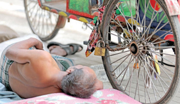 Exhausted from the day’s work, an auto-rickshaw puller takes a midday nap beside his vehicle, which is locked to prevent theft, at Bijoy Sarani on Sunday. -Kamrul Islam Ratan