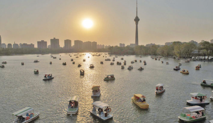 People enjoy sunset boat rides in the Yuyuantan park in Beijing, 24 March 2019.